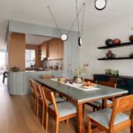 Jedáleň s robustným dreveným stolom, sivou vrchnou doskou a dizajnovým čiernym svietidlom.