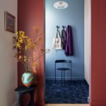 Chodba s výraznou modrou dlažbou, modrými a červenými stenami a čiernym dizajnovým stolíkom.