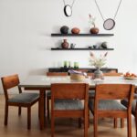 edáleň s tmavými drevenými stoličkami, sivým stolom a čiernymi otvorenými policami.