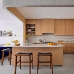 Kuchyňa s prírodnou drevenou linkou, mramorovým obkladom a svetlou vzorovanou podlahou.