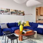 Obývacia izba s modrou modulárnou pohovkou, nízkym dreveným stolíkom a bielymi textilnými lustrami.