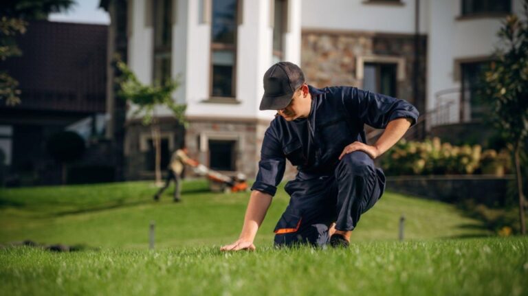 Muž kľačí na trávniku dotýka sa ho rukou.