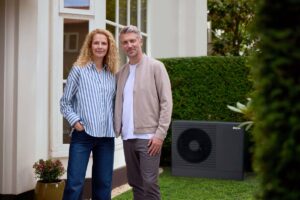 Muž a žena v zrelom veku pri dome s tepelným čerpadlom.