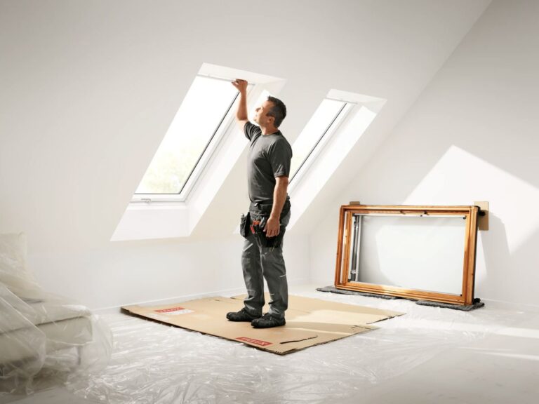 Muž sa díva von strešným oknom po ich výmene za nové.