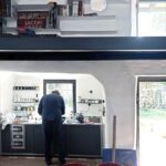 Kuchyňa v rustikálnom štýle s čiernou pracovnou doskou, bielymi policami a masívnou drevenou podlahou.