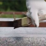 Detail na natieranie kovového zábradlia hnedou farbou.