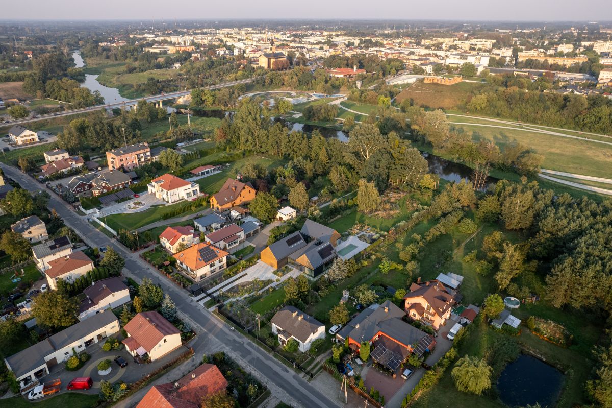 Pohľad z dronu na dom pri rieke, okolitú zástavbu a blízke mesto.