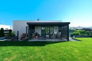 Pergola pri modernom rodinnom domes vonkajším sedením a kvetinami pri upravenom dvore.