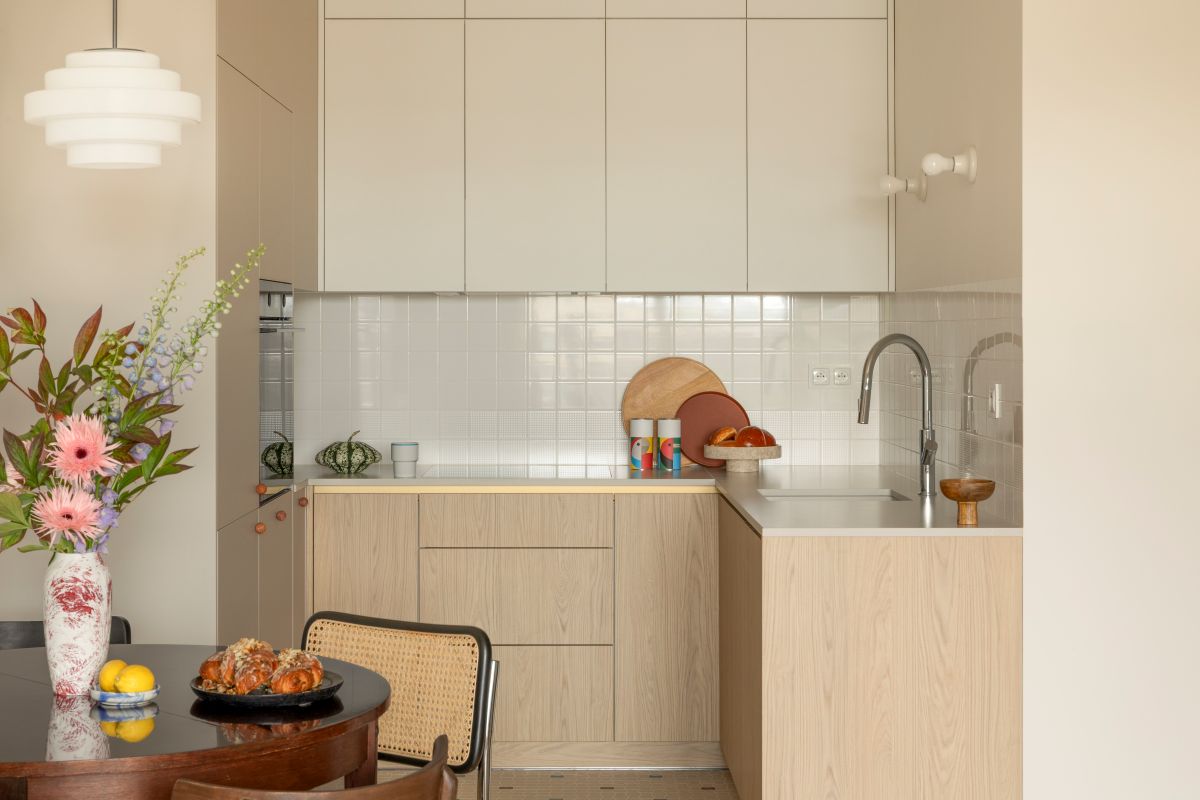 Kuchyňa s krémovými skrinkami, drevenou linkou a okrúhlym jedálenským stolom.