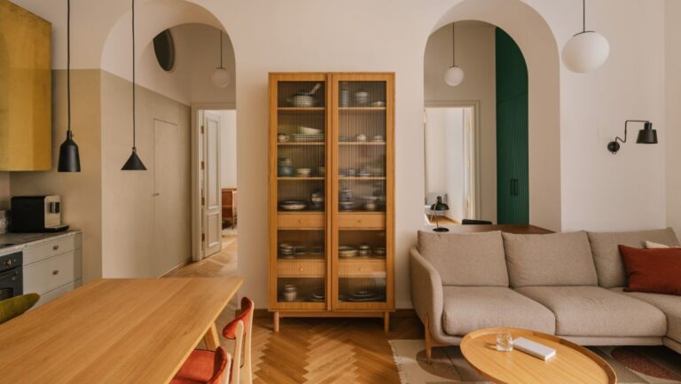 Obývacia izba s dubovou vitrínou, oblúkovými priechodmi a sivou čalúnenou pohovkou.